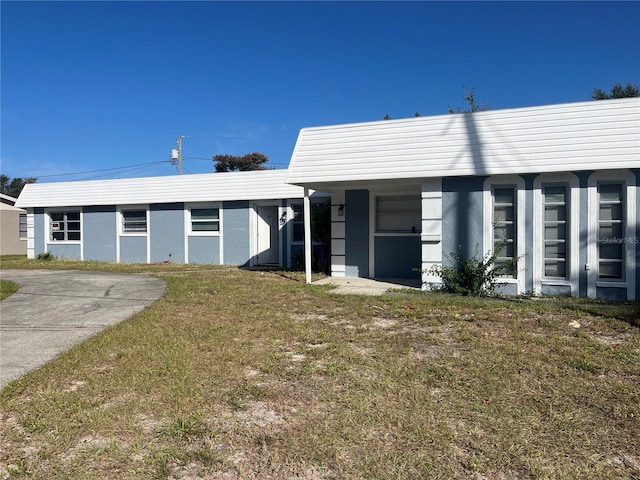 single story home featuring a front lawn and a carport