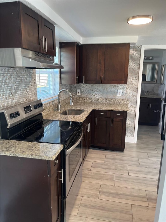 kitchen with backsplash, light stone countertops, sink, and stainless steel range with electric cooktop