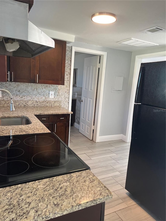 kitchen with black appliances, sink, dark brown cabinetry, range hood, and decorative backsplash