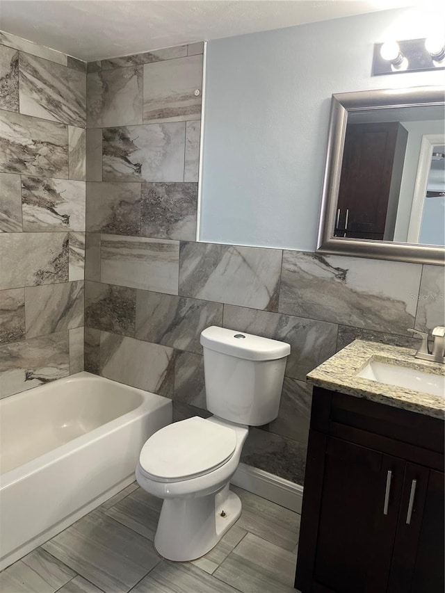 bathroom with tile walls, vanity, and toilet