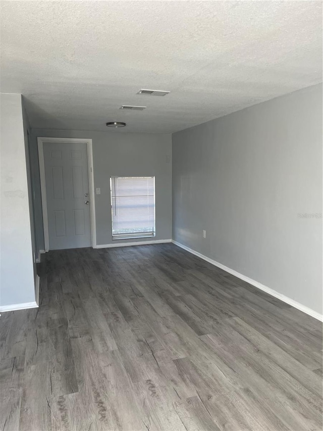 empty room with wood-type flooring and a textured ceiling