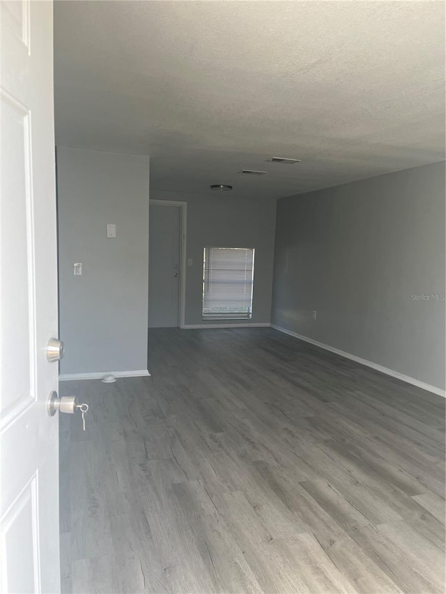 empty room with hardwood / wood-style floors and a textured ceiling