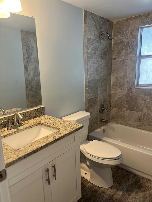 full bathroom featuring tiled shower / bath, vanity, wood-type flooring, and toilet