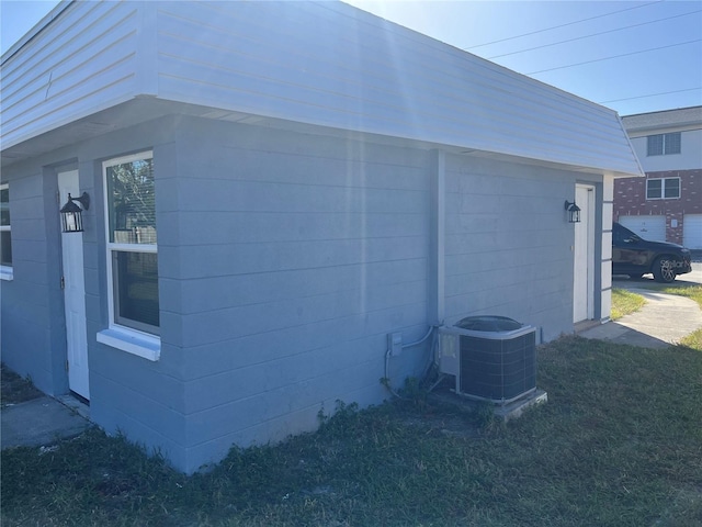 view of side of home featuring a lawn and central AC unit