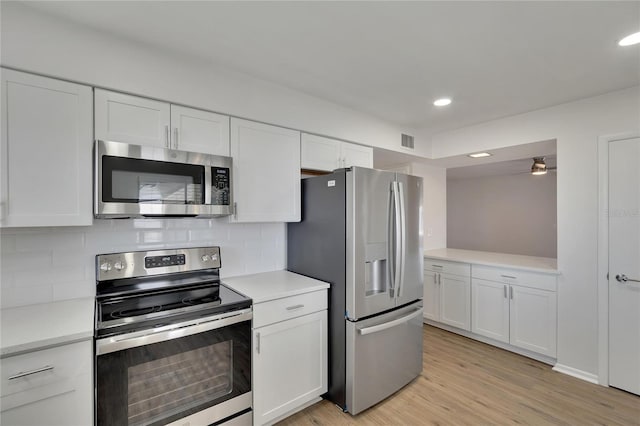 kitchen with white cabinets, tasteful backsplash, ceiling fan, light hardwood / wood-style floors, and stainless steel appliances