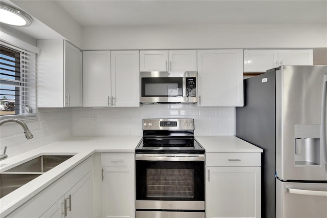 kitchen with decorative backsplash, white cabinets, stainless steel appliances, and sink