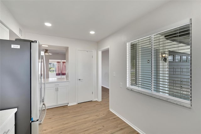 kitchen with stainless steel fridge, light hardwood / wood-style flooring, and white cabinetry