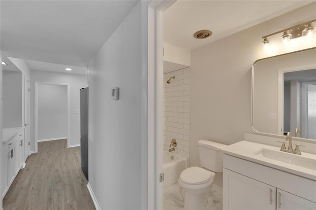 full bathroom featuring tiled shower / bath, vanity, hardwood / wood-style floors, and toilet