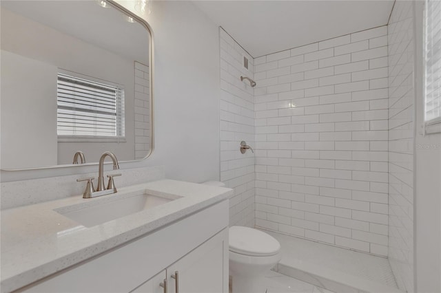 bathroom featuring vanity, a tile shower, and toilet