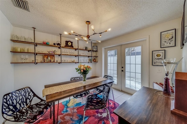 tiled dining area featuring french doors, a notable chandelier, and a textured ceiling