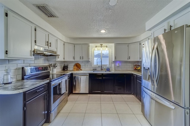 kitchen featuring decorative backsplash, light tile patterned floors, a textured ceiling, sink, and stainless steel appliances