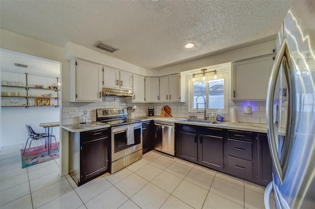 kitchen featuring stainless steel appliances, sink, light tile patterned floors, white cabinetry, and tasteful backsplash