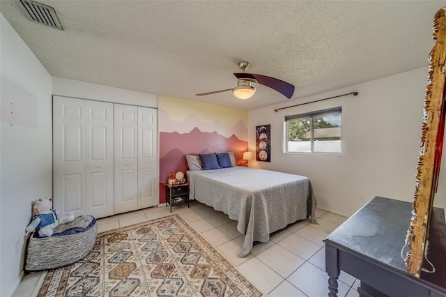 bedroom featuring a closet, a textured ceiling, light tile patterned floors, and ceiling fan