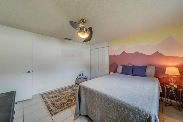 bedroom with a closet, ceiling fan, a textured ceiling, and light tile patterned flooring