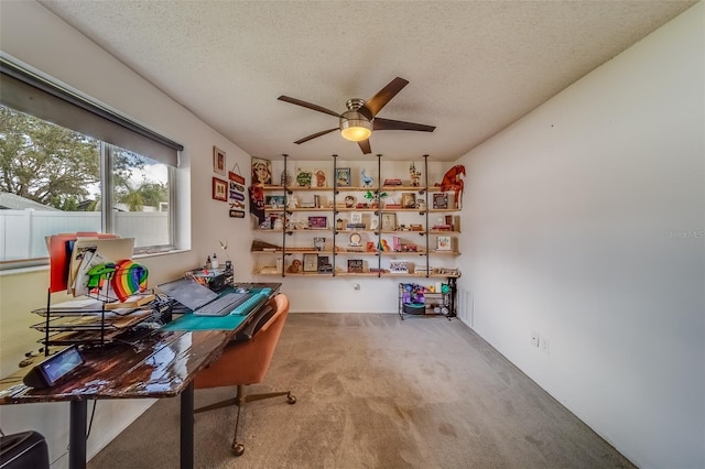 carpeted office space with a textured ceiling and ceiling fan