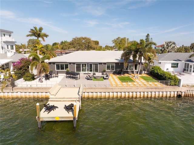 back of property with a water view and a patio area