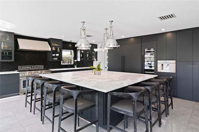 kitchen featuring a spacious island, appliances with stainless steel finishes, decorative light fixtures, and ventilation hood