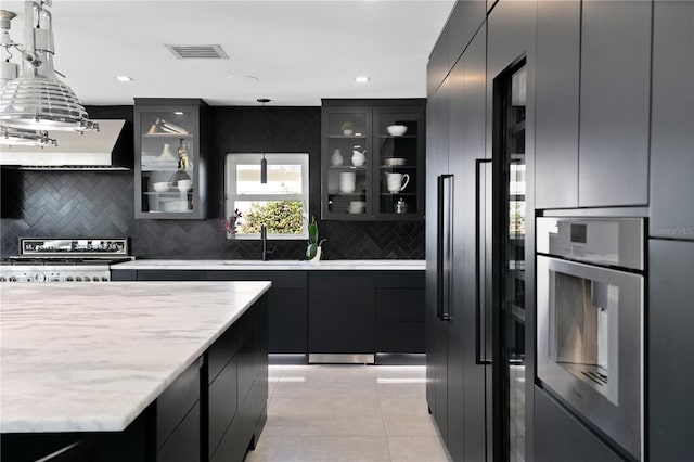 kitchen featuring decorative backsplash, decorative light fixtures, ventilation hood, and stainless steel appliances