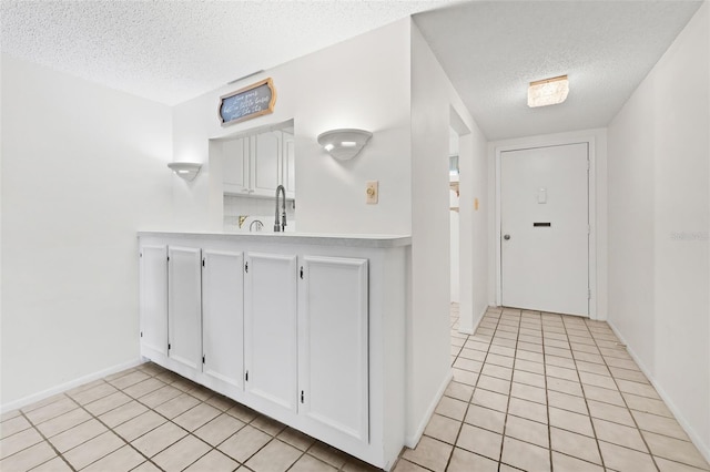3361 Scorecard Dr Unit 0, New Port Richey, FL 34655 - kitchen with a textured ceiling, light tile patterned flooring, white cabinetry, light countertops, and baseboards