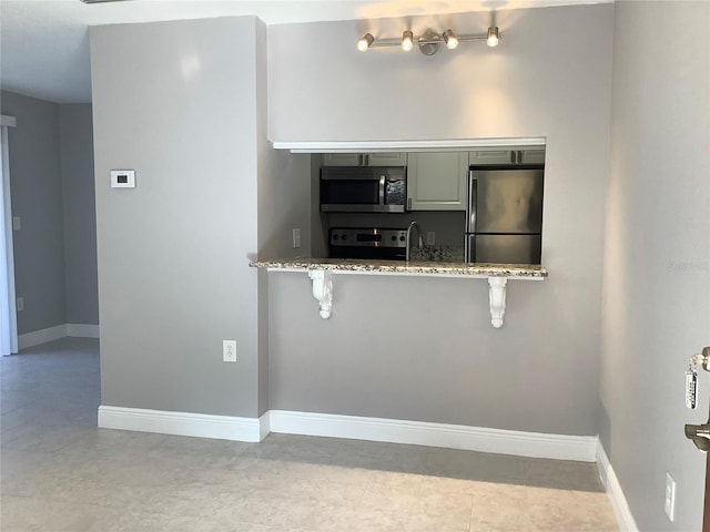 kitchen featuring a kitchen bar, stainless steel appliances, and light stone counters