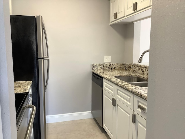 kitchen featuring white cabinets, light tile patterned floors, sink, light stone countertops, and appliances with stainless steel finishes