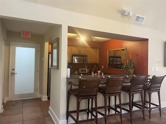 kitchen with a kitchen breakfast bar, kitchen peninsula, and dark tile patterned flooring