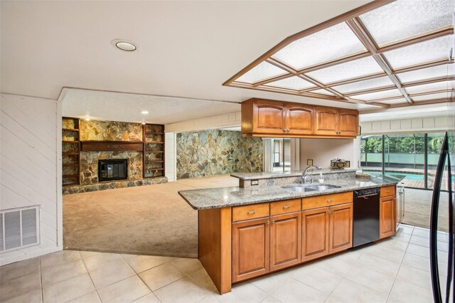 kitchen with light stone countertops, a fireplace, black dishwasher, light colored carpet, and kitchen peninsula