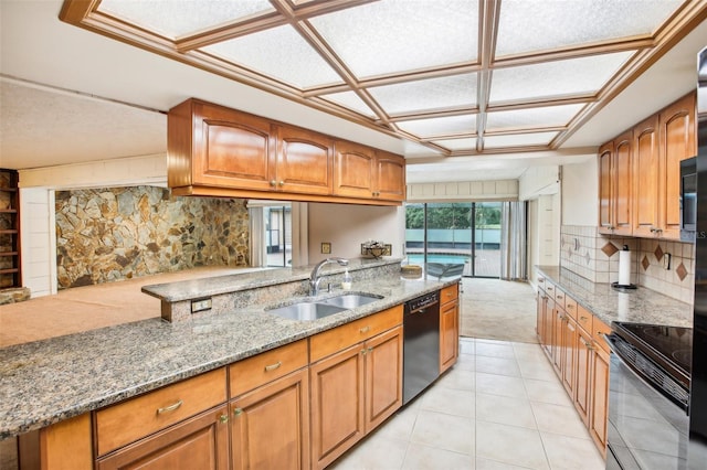 kitchen with sink, tasteful backsplash, light stone counters, kitchen peninsula, and black appliances