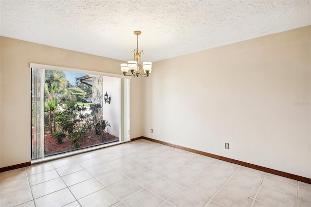 empty room with a textured ceiling, a notable chandelier, and light tile patterned flooring