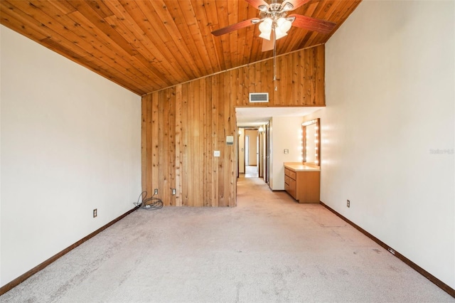 spare room featuring wood walls, vaulted ceiling, ceiling fan, light colored carpet, and wood ceiling