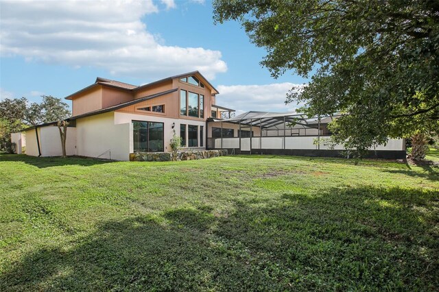 rear view of property with a lawn and glass enclosure