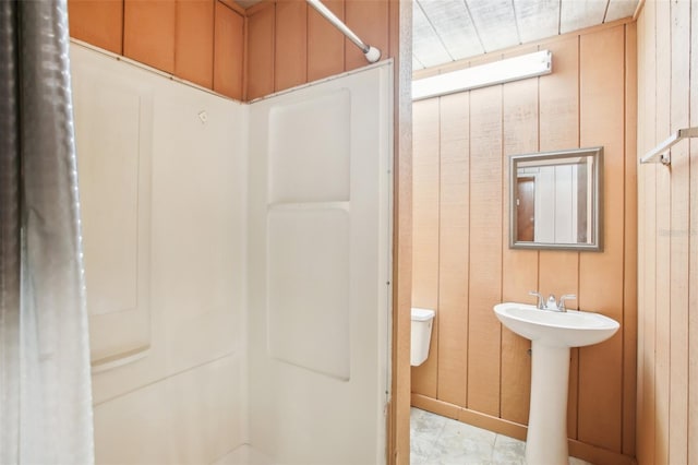 bathroom featuring wood walls, sink, and walk in shower