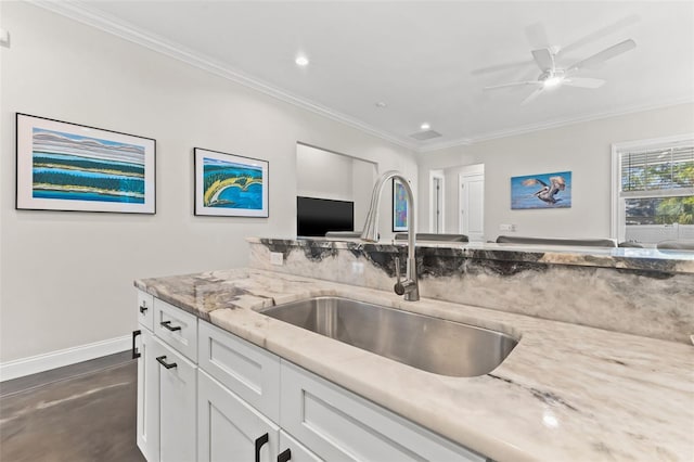 kitchen featuring white cabinets, crown molding, light stone counters, and sink