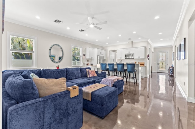 living room with ornamental molding, concrete floors, ceiling fan, and a healthy amount of sunlight