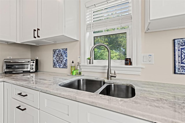 kitchen featuring white cabinetry, sink, and light stone counters