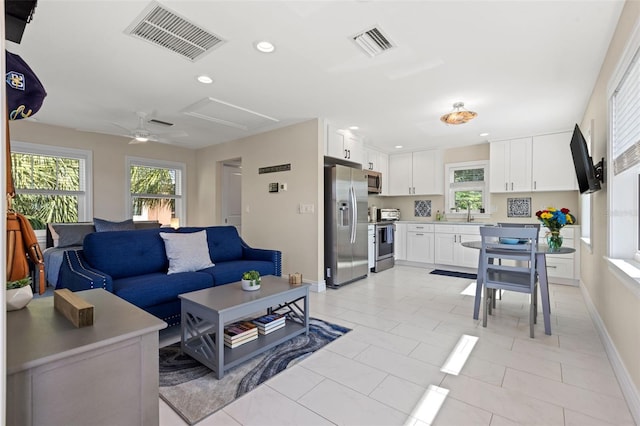 living room featuring ceiling fan, light tile patterned floors, and sink