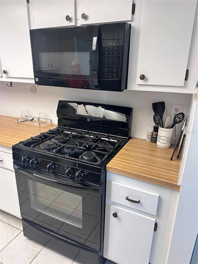 kitchen with white cabinetry, black appliances, and light tile patterned flooring