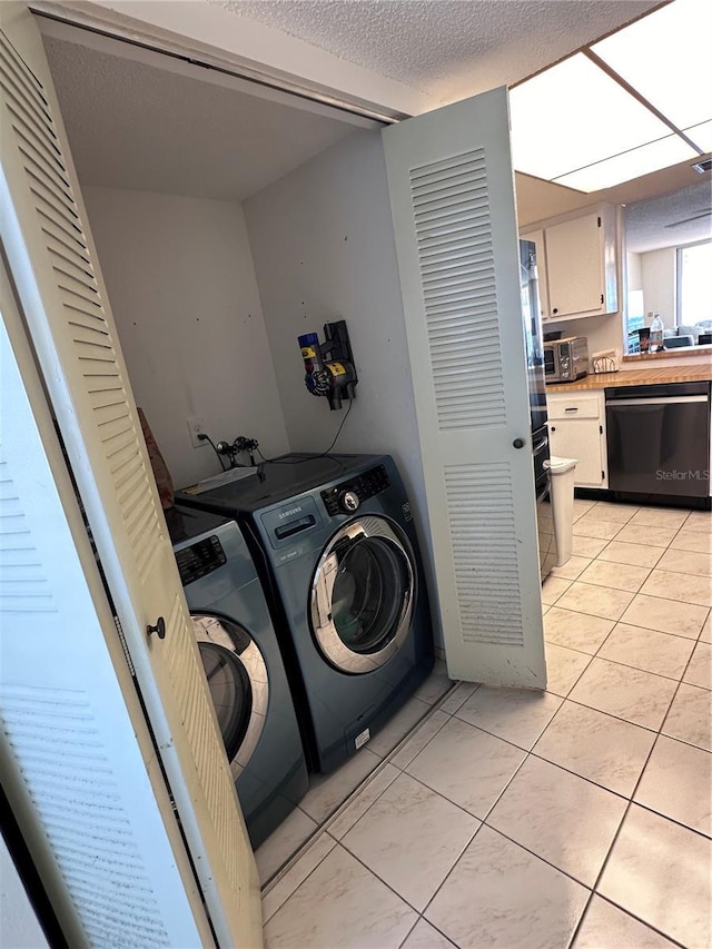 clothes washing area featuring independent washer and dryer, light tile patterned floors, and a textured ceiling