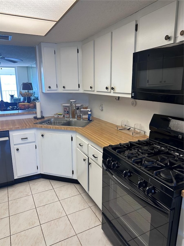 kitchen with light tile patterned floors, a textured ceiling, white cabinetry, black appliances, and sink