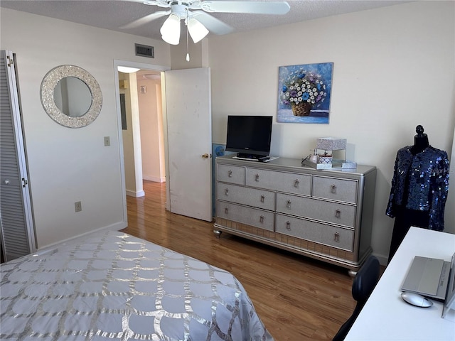 bedroom with a textured ceiling, hardwood / wood-style flooring, and ceiling fan