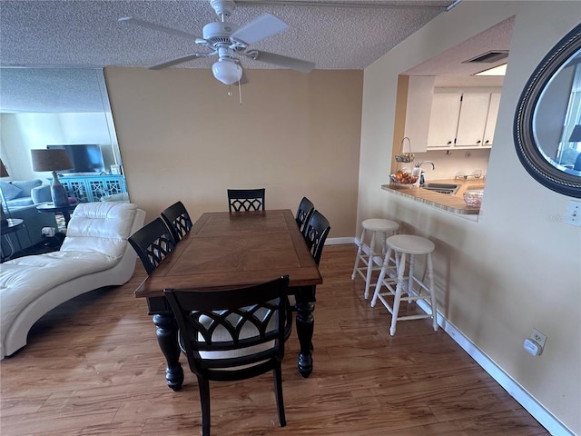 dining room featuring a textured ceiling, sink, wood-type flooring, and ceiling fan