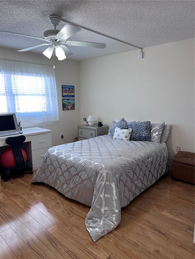 bedroom with wood finished floors, a textured ceiling, ceiling fan, and an office area