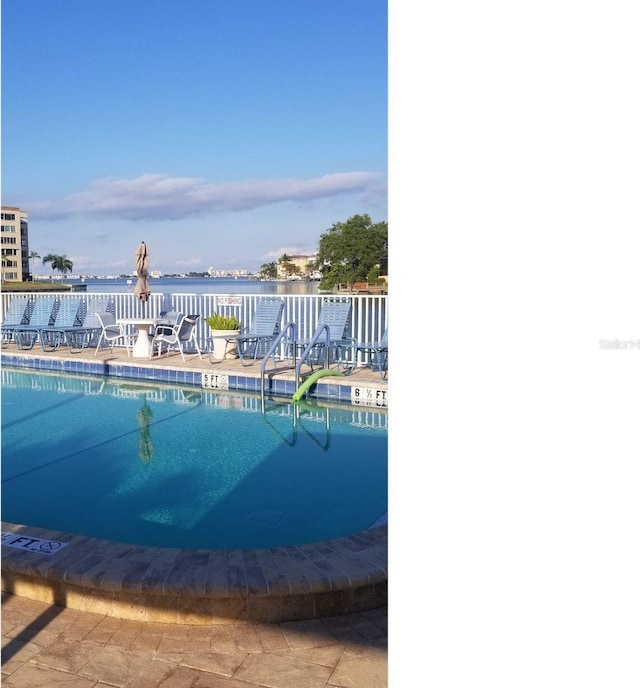 view of swimming pool featuring a water view and a patio area