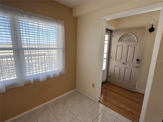 foyer entrance featuring healthy amount of natural light, light tile patterned floors, and baseboards
