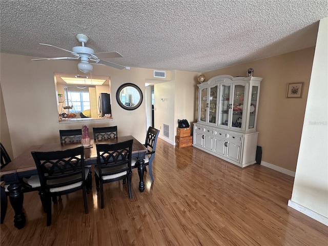 dining room with ceiling fan, wood finished floors, baseboards, and a textured ceiling