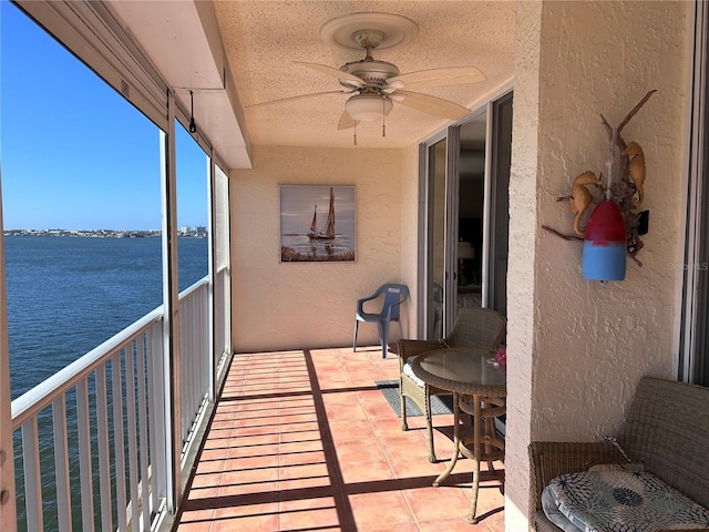 balcony featuring a water view and a ceiling fan