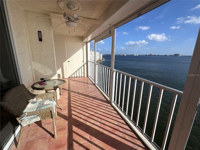 balcony featuring a ceiling fan and a water view