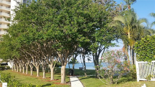 surrounding community with a water view and a yard