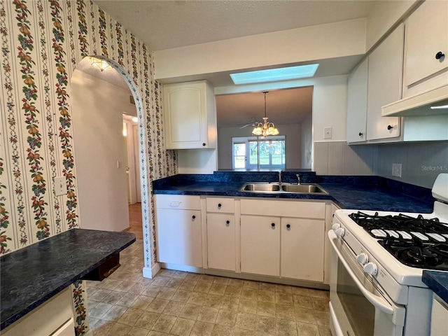 kitchen with white cabinetry, sink, white range with gas cooktop, a skylight, and a chandelier