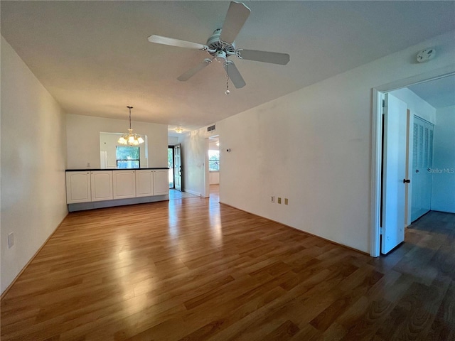 interior space featuring ceiling fan with notable chandelier and hardwood / wood-style flooring